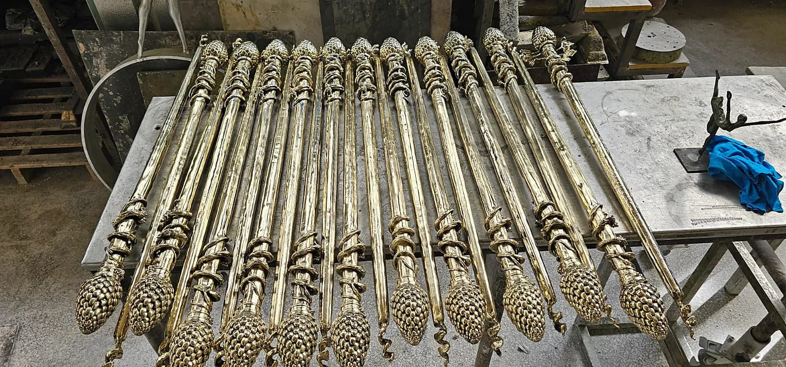 Rows of gilded bronze thyrsi laid out on the workshop bench